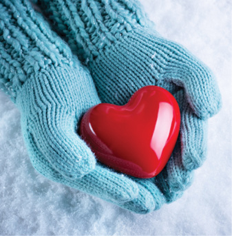 close up of hand wearing light blue winter gloves holding a red heart shaped stone