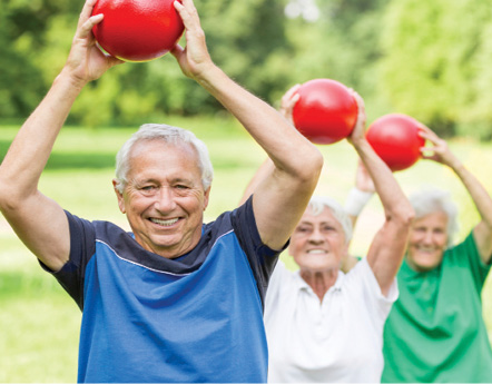 senior folks exercising in the park. Holding red weighted exercise balls.
