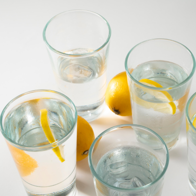 Clear glasses filled with water, wedges of lemon sitting on white table